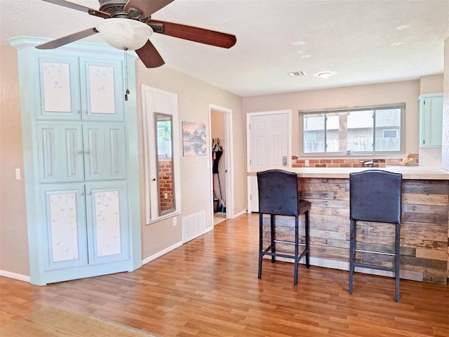 2901 Maple Ln, Edmond, OK 73034 - kitchen with a breakfast bar, light wood-style flooring, light countertops, a peninsula, and a ceiling fan