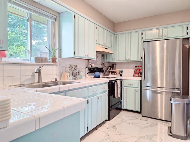 2901 Maple Ln, Edmond, OK 73034 - kitchen featuring freestanding refrigerator, electric range, light marble finish floors, tile counters, and under cabinet range hood