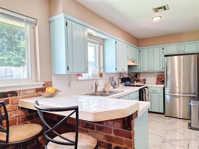 2901 Maple Ln, Edmond, OK 73034 - kitchen with freestanding refrigerator, electric range, light marble finish floors, tile counters, and under cabinet range hood