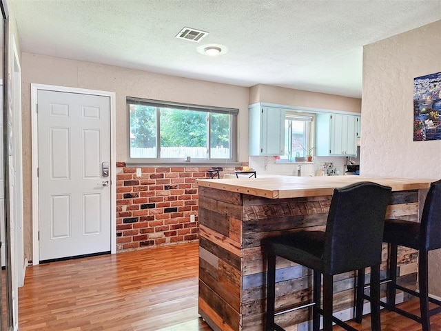 2901 Maple Ln, Edmond, OK 73034 - bar area with light wood finished floors, a textured ceiling, and a textured wall