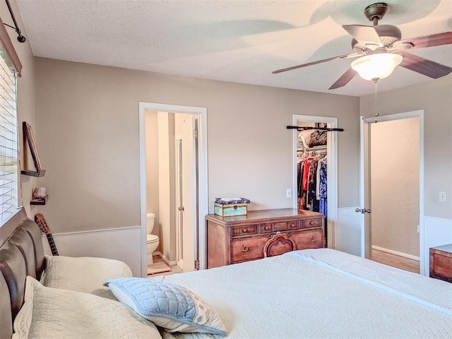 2901 Maple Ln, Edmond, OK 73034 - bedroom with a spacious closet, connected bathroom, a ceiling fan, and a textured ceiling