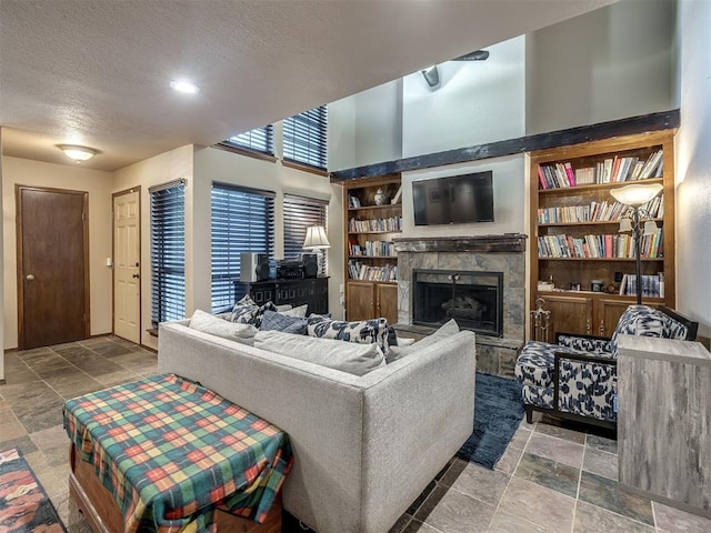 6500 N Grand Blvd Unit 131, Oklahoma City, OK 73116 - living room featuring a textured ceiling, a fireplace with raised hearth, built in features, stone tile flooring, and recessed lighting