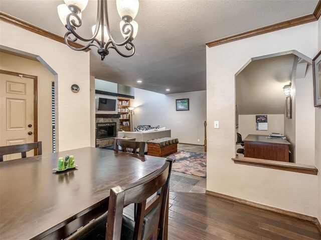 6500 N Grand Blvd Unit 131, Oklahoma City, OK 73116 - dining room with arched walkways, a stone fireplace, crown molding, a chandelier, and dark wood-type flooring