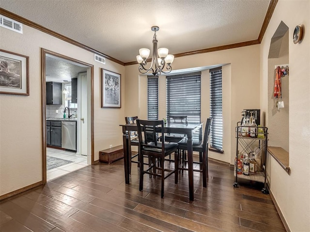 6500 N Grand Blvd Unit 131, Oklahoma City, OK 73116 - dining area featuring crown molding, a chandelier, a textured ceiling, wood finished floors, and a textured wall