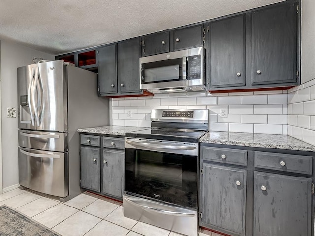 6500 N Grand Blvd Unit 131, Oklahoma City, OK 73116 - kitchen featuring appliances with stainless steel finishes, backsplash, light tile patterned flooring, a textured ceiling, and gray cabinets