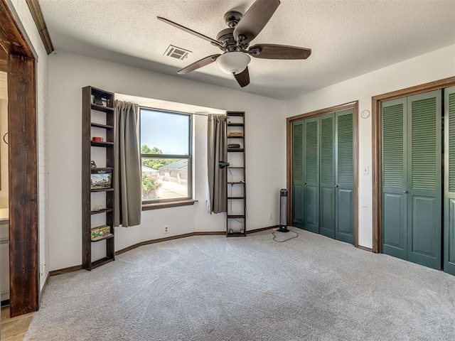 6500 N Grand Blvd Unit 131, Oklahoma City, OK 73116 - unfurnished bedroom with carpet floors, a textured ceiling, multiple closets, and a ceiling fan