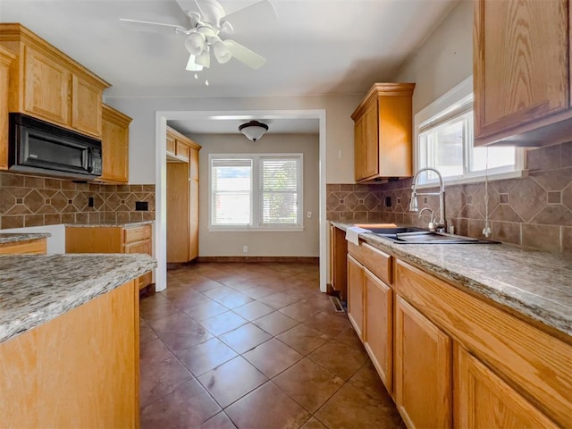 2437 NW 36th Ter, Oklahoma City, OK 73112 - kitchen with black microwave, decorative backsplash, ceiling fan, and light stone counters