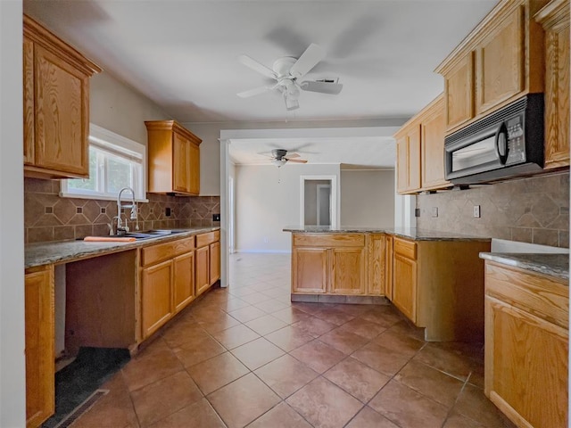 2437 NW 36th Ter, Oklahoma City, OK 73112 - kitchen featuring black microwave, tasteful backsplash, ceiling fan, tile patterned floors, and a peninsula