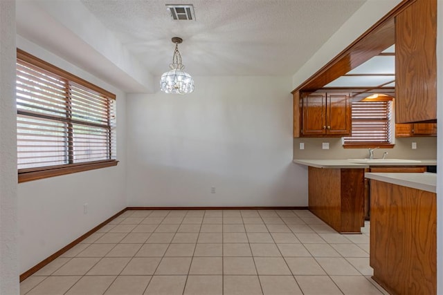 3116 SW 96th St, Oklahoma City, OK 73159 - kitchen with light countertops, brown cabinets, pendant lighting, a peninsula, and a chandelier