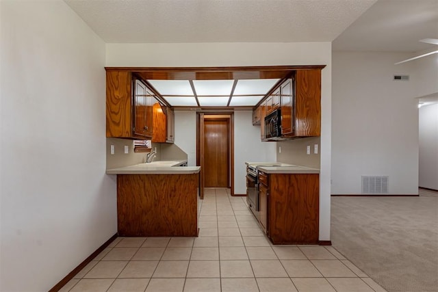 3116 SW 96th St, Oklahoma City, OK 73159 - kitchen with stainless steel electric range, black microwave, light countertops, and brown cabinets
