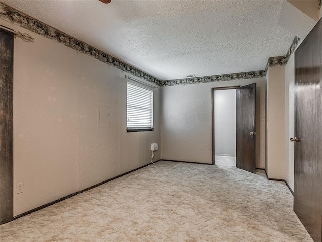 924 Penn Ln, Moore, OK 73160 - empty room featuring a textured ceiling, carpet flooring, and a textured wall