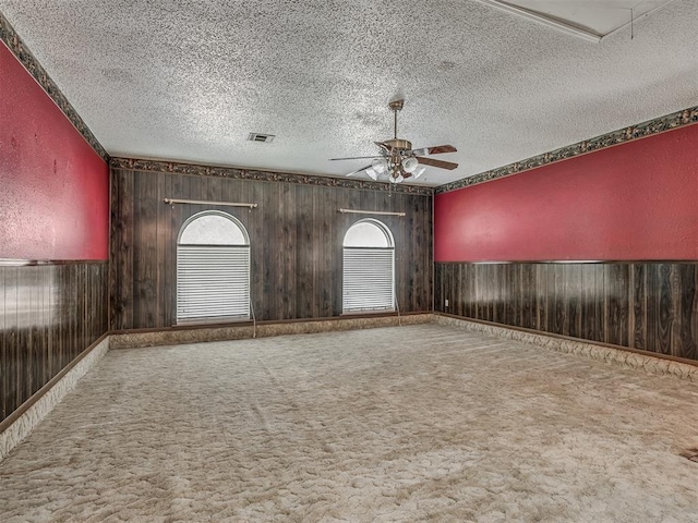 924 Penn Ln, Moore, OK 73160 - unfurnished room featuring ceiling fan, wooden walls, a textured ceiling, carpet flooring, and wainscoting