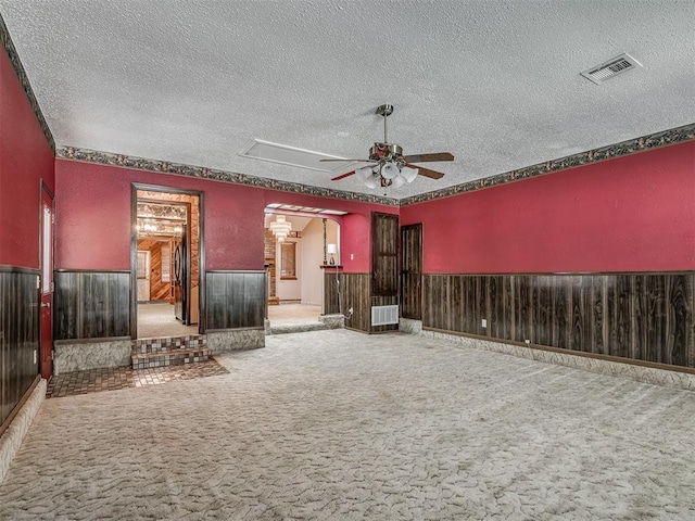 924 Penn Ln, Moore, OK 73160 - unfurnished living room featuring ceiling fan, a textured ceiling, carpet floors, wainscoting, and arched walkways