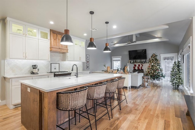 833 Gathering Leaves Way Unit 9183810100, Edmond, OK 73034 - kitchen with decorative backsplash, white cabinets, light wood-style floors, light countertops, and a center island with sink