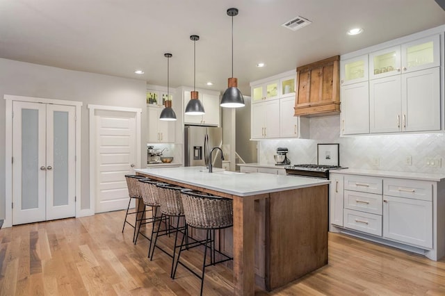 833 Gathering Leaves Way Unit 9183810100, Edmond, OK 73034 - kitchen featuring stainless steel refrigerator with ice dispenser, custom range hood, a breakfast bar area, decorative backsplash, and recessed lighting