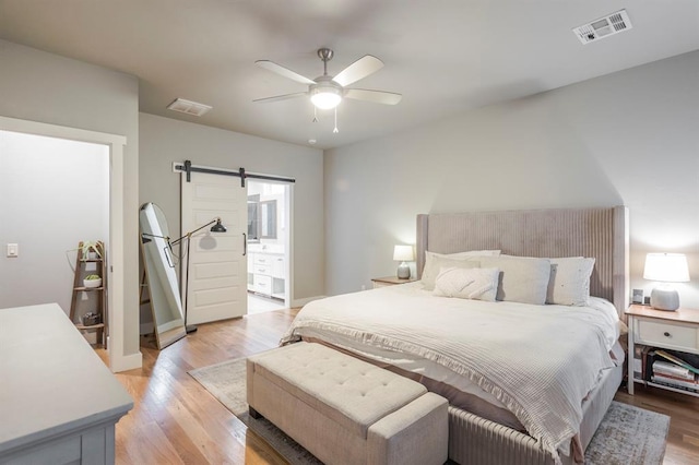 833 Gathering Leaves Way Unit 9183810100, Edmond, OK 73034 - bedroom featuring a barn door, light wood-type flooring, a ceiling fan, and ensuite bathroom