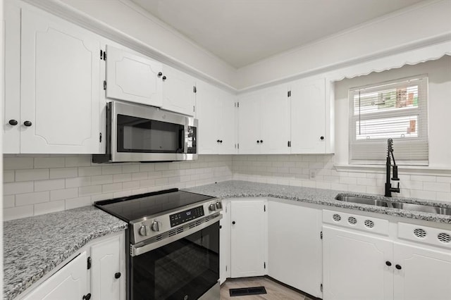 2525 NW 32nd St, Oklahoma City, OK 73112 - kitchen featuring stainless steel appliances, white cabinets, decorative backsplash, and light stone countertops