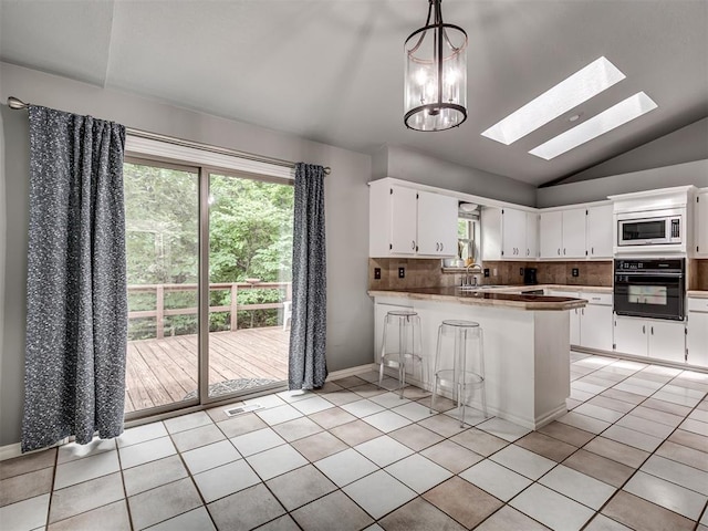 5101 Long Branch Ln, Edmond, OK 73034 - kitchen with oven, stainless steel microwave, a peninsula, vaulted ceiling, and tasteful backsplash