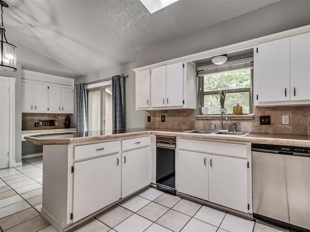 5101 Long Branch Ln, Edmond, OK 73034 - kitchen with stainless steel dishwasher, white cabinets, tasteful backsplash, a peninsula, and vaulted ceiling