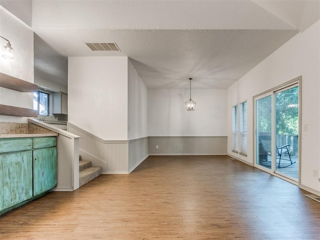 1404 Mary Lee Ln, Edmond, OK 73034 - unfurnished dining area with light wood finished floors, wainscoting, a chandelier, stairs, and a textured ceiling