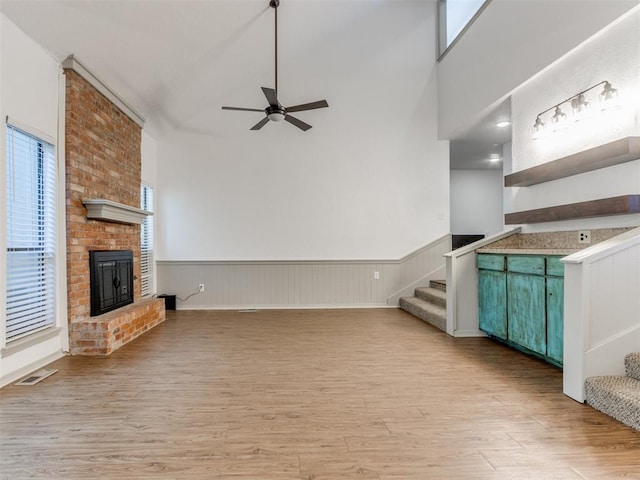 1404 Mary Lee Ln, Edmond, OK 73034 - unfurnished living room featuring ceiling fan, plenty of natural light, stairway, light wood finished floors, and wainscoting