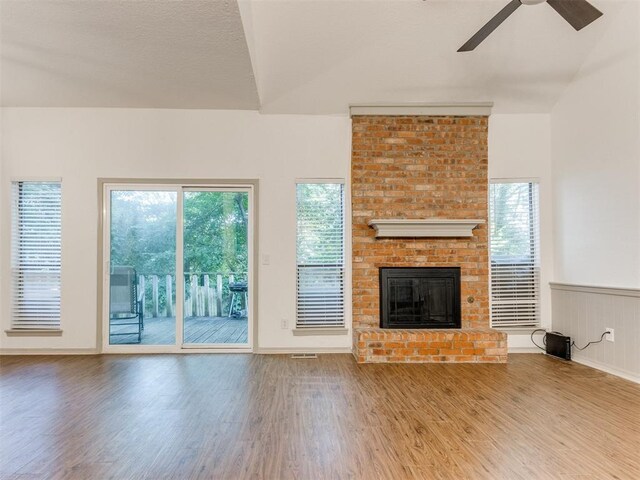 1404 Mary Lee Ln, Edmond, OK 73034 - unfurnished living room featuring a ceiling fan, wood finished floors, a brick fireplace, lofted ceiling, and wainscoting