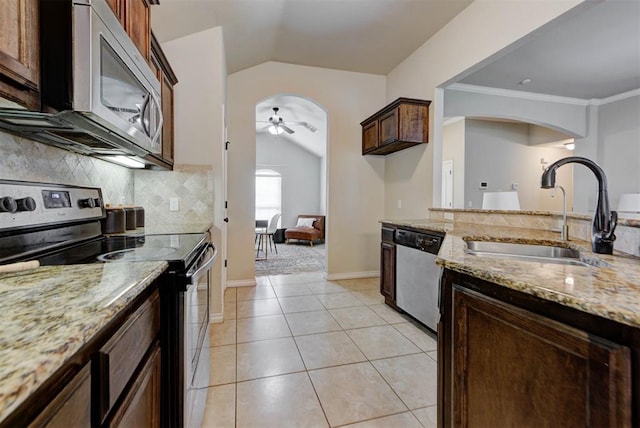 9909 Summerhill Ln, Yukon, OK 73099 - kitchen featuring stainless steel appliances, vaulted ceiling, a ceiling fan, arched walkways, and light stone counters
