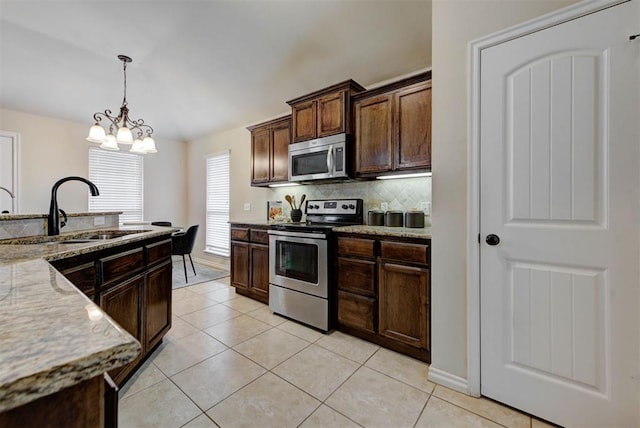 9909 Summerhill Ln, Yukon, OK 73099 - kitchen with stainless steel appliances, hanging light fixtures, light stone countertops, backsplash, and dark brown cabinets