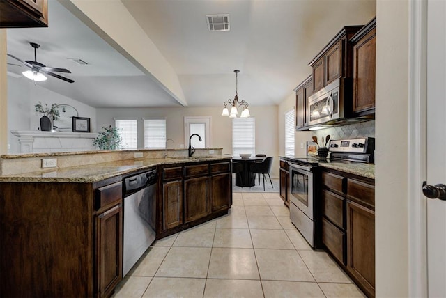 9909 Summerhill Ln, Yukon, OK 73099 - kitchen featuring appliances with stainless steel finishes, tasteful backsplash, light tile patterned flooring, a chandelier, and dark brown cabinetry