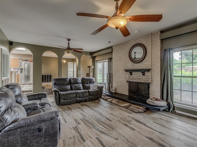 3700 N Edgewater Dr, Oklahoma City, OK 73116 - living area with a ceiling fan, a fireplace, arched walkways, and light wood finished floors