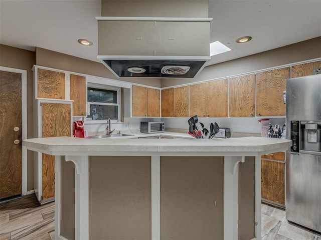 3700 N Edgewater Dr, Oklahoma City, OK 73116 - kitchen featuring stainless steel refrigerator with ice dispenser, light countertops, a skylight, light wood-style flooring, and recessed lighting