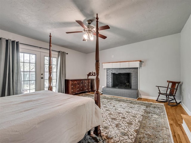531 NW 48th St, Oklahoma City, OK 73118 - bedroom with a textured ceiling, access to exterior, wood finished floors, a fireplace, and french doors