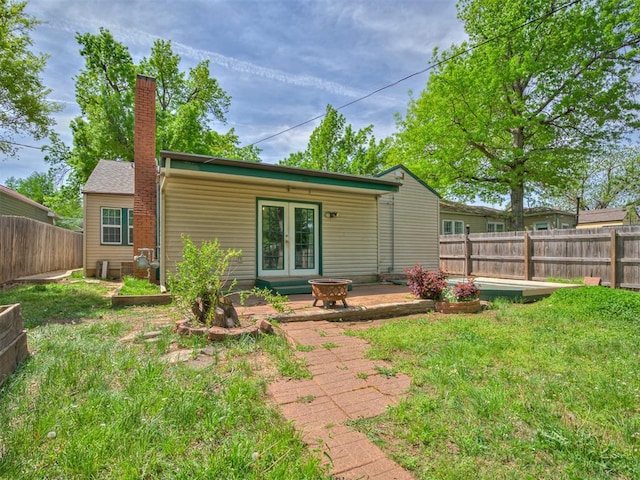531 NW 48th St, Oklahoma City, OK 73118 - rear view of house featuring a fenced backyard, a chimney, french doors, and a patio