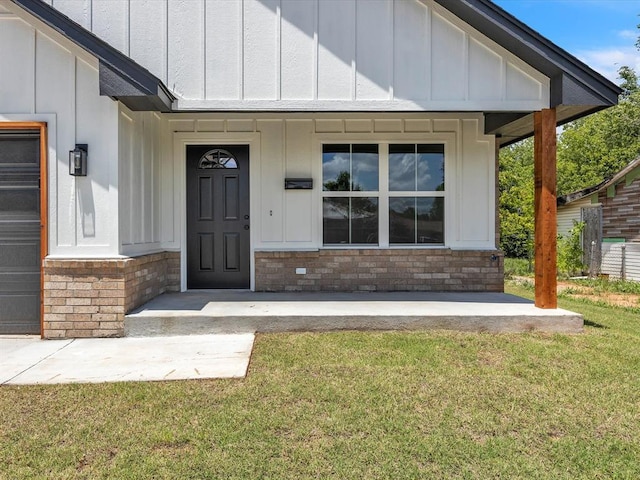 1609 NE 26th St, Oklahoma City, OK 73111 - view of exterior entry with board and batten siding, a yard, and stone siding