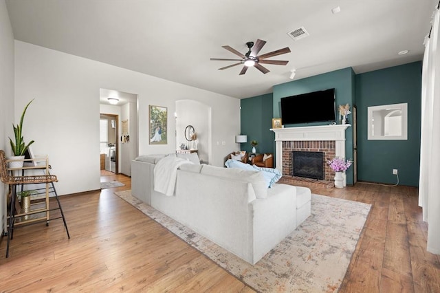 18200 Allora Dr, Edmond, OK 73012 - living area featuring a ceiling fan, a brick fireplace, hardwood / wood-style flooring, and arched walkways