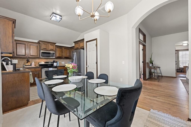 18200 Allora Dr, Edmond, OK 73012 - dining room with arched walkways, lofted ceiling, light wood-style floors, and a chandelier