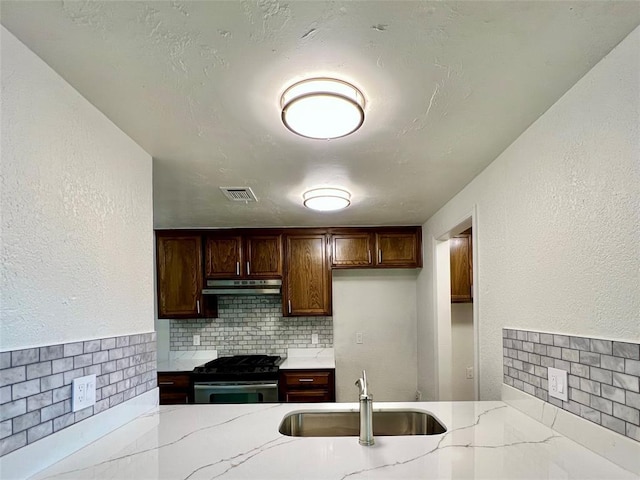 12519 SW 2nd St, Yukon, OK 73099 - kitchen with gas stove, under cabinet range hood, decorative backsplash, and light stone countertops