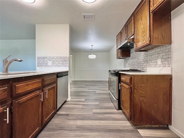 12519 SW 2nd St, Yukon, OK 73099 - kitchen featuring appliances with stainless steel finishes, tasteful backsplash, wood finished floors, and light countertops