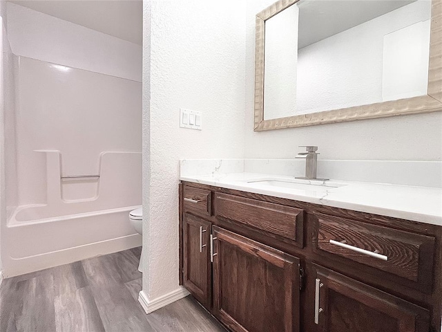 12519 SW 2nd St, Yukon, OK 73099 - bathroom featuring vanity, wood finished floors, shower / bathtub combination, and a textured wall