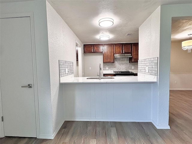 12517 SW 2nd St, Yukon, OK 73099 - kitchen with under cabinet range hood, wood finished floors, range, decorative backsplash, and a textured wall