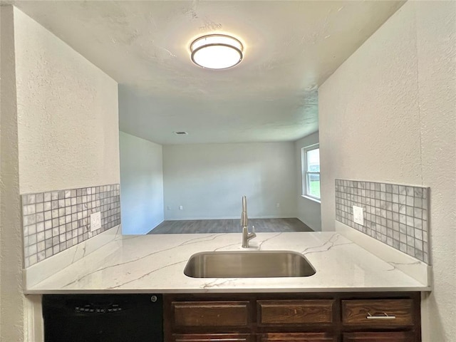 12517 SW 2nd St, Yukon, OK 73099 - kitchen with black dishwasher, a textured wall, light stone countertops, wood finished floors, and dark brown cabinets