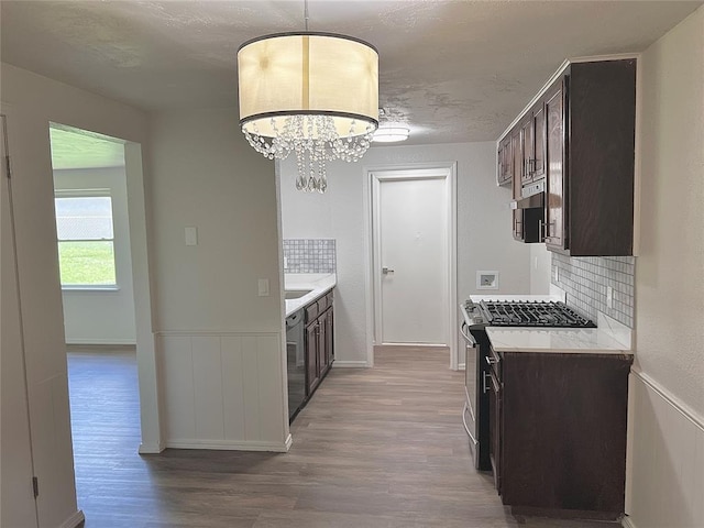12517 SW 2nd St, Yukon, OK 73099 - kitchen featuring gas range, dark brown cabinetry, wood finished floors, tasteful backsplash, and a wainscoted wall