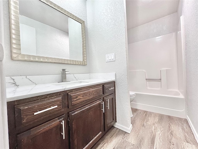 12517 SW 2nd St, Yukon, OK 73099 - bathroom featuring a textured wall, wood finished floors, vanity, and washtub / shower combination