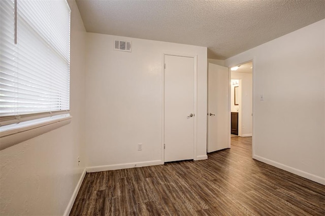 4025 Parkwoods Ln, Midwest City, OK 73110 - unfurnished bedroom with dark wood-type flooring and a textured ceiling