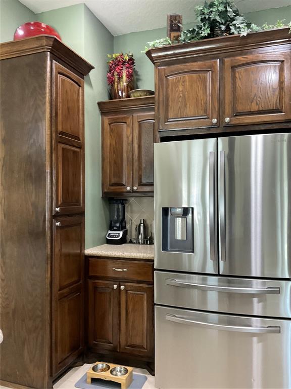 10201 Pinckney Ct, Oklahoma City, OK 73162 - kitchen with stainless steel fridge with ice dispenser, light countertops, tasteful backsplash, and dark brown cabinets