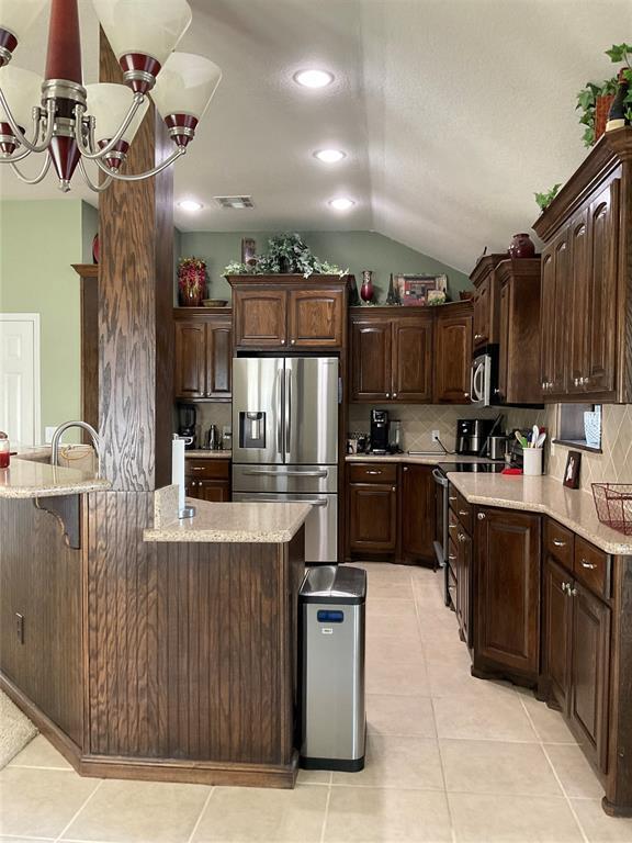 10201 Pinckney Ct, Oklahoma City, OK 73162 - kitchen featuring appliances with stainless steel finishes, vaulted ceiling, dark brown cabinets, backsplash, and recessed lighting