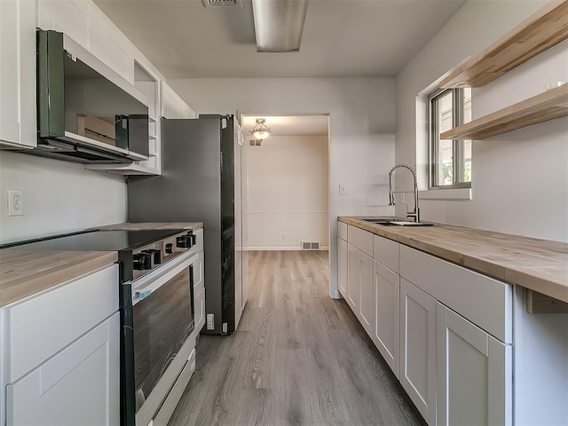 2632 SW 55th St, Oklahoma City, OK 73119 - kitchen featuring stainless steel range with electric cooktop, wooden counters, open shelves, light wood-style floors, and white cabinets