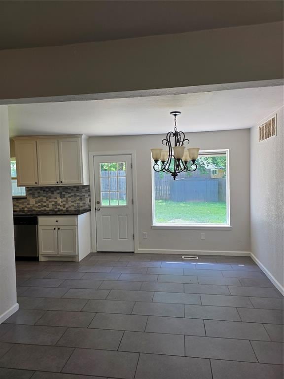 8813 Aaron Dr, Oklahoma City, OK 73132 - unfurnished dining area with a chandelier and dark tile patterned flooring