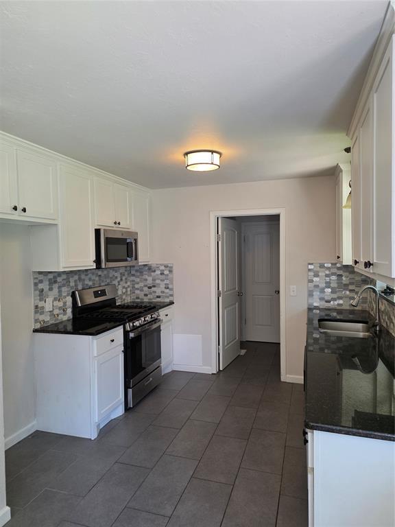 8813 Aaron Dr, Oklahoma City, OK 73132 - kitchen featuring stainless steel appliances, decorative backsplash, and white cabinets