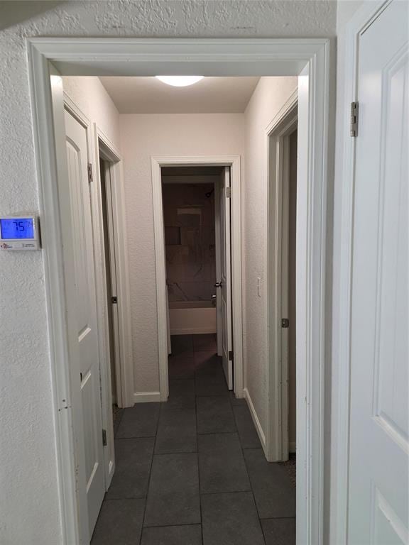 8813 Aaron Dr, Oklahoma City, OK 73132 - corridor featuring dark tile patterned floors and baseboards